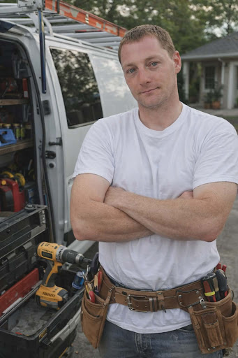 Local Venice, FL handyman from Fix It Once smiling with a cordless drill in front of a home